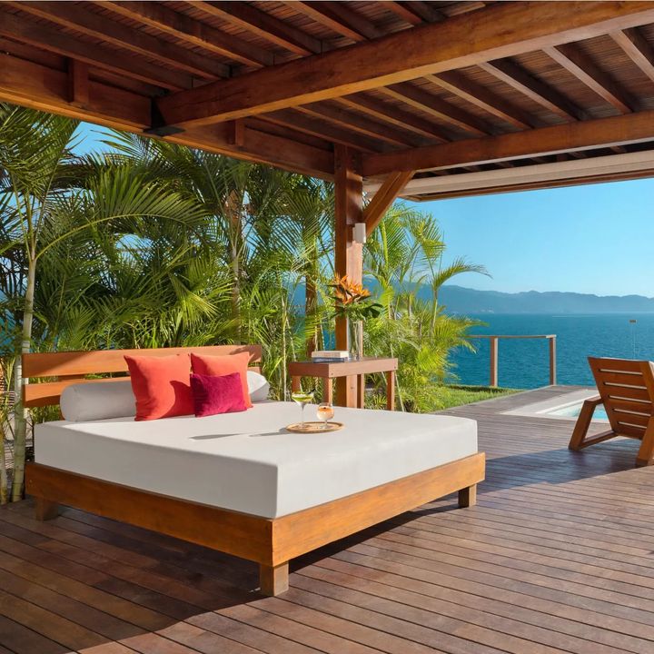 A sunbed, lounge chairs, and infinity pool looking out at the ocean at Dreams Vallarta Bay Resort & Spa.