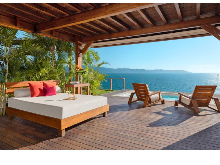 A sunbed, lounge chairs, and infinity pool looking out at the ocean at Dreams Vallarta Bay Resort & Spa.