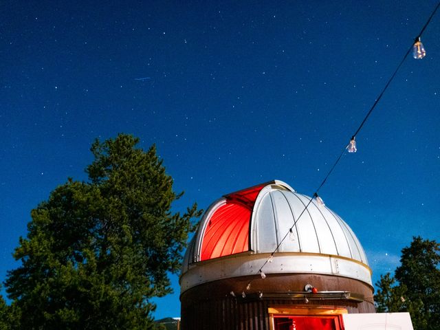 An observatory with red lighting coming from within and trees and string lights outside.