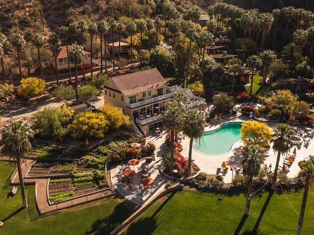 An aerial daytime view of Castle Hot Springs with a lodge and pool surrounded by trees and grass.