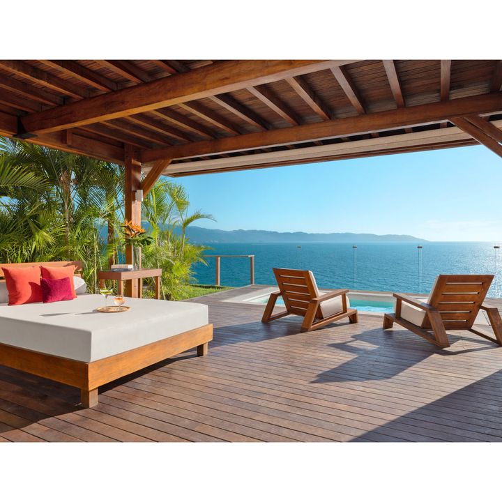 A sunbed, lounge chairs, and infinity pool looking out at the ocean at Dreams Vallarta Bay Resort & Spa.