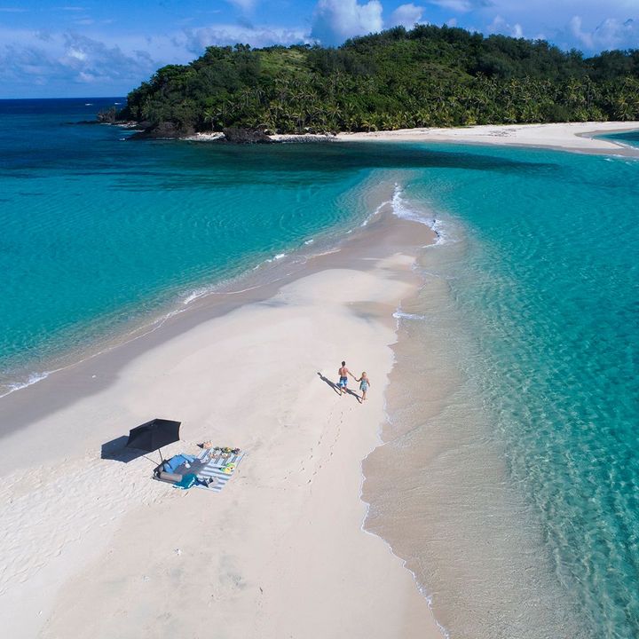 A sandbar stretch of sand between turquoise water leading to a small island at Yasawa Island Resort.