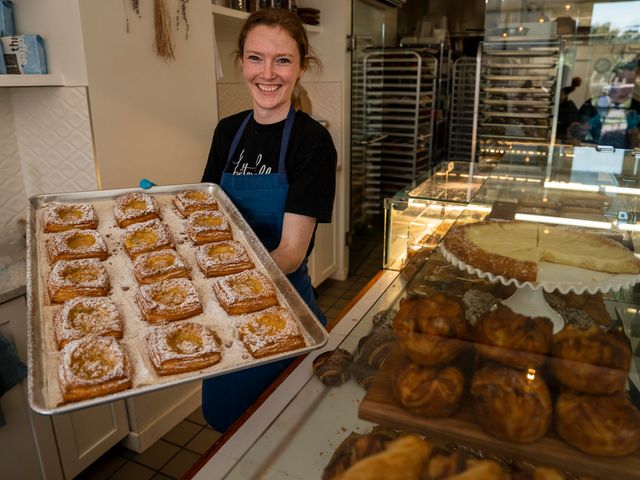 A female worker at Butter Block shows off powdered-sugar-covered pastries on a tray in the kitchen