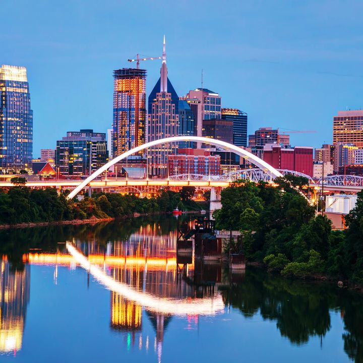 The Nashville skyline at night as seen from the river with the buildings and bridge lit up.