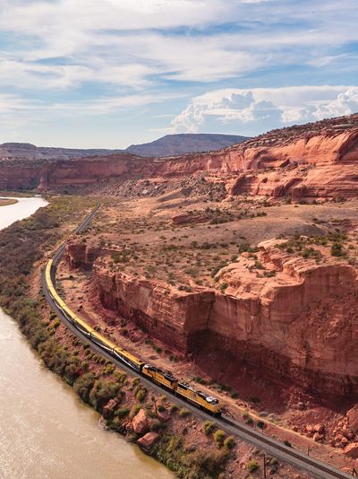 A Canyon Spirit train next to a river and Utah's red rock formations.