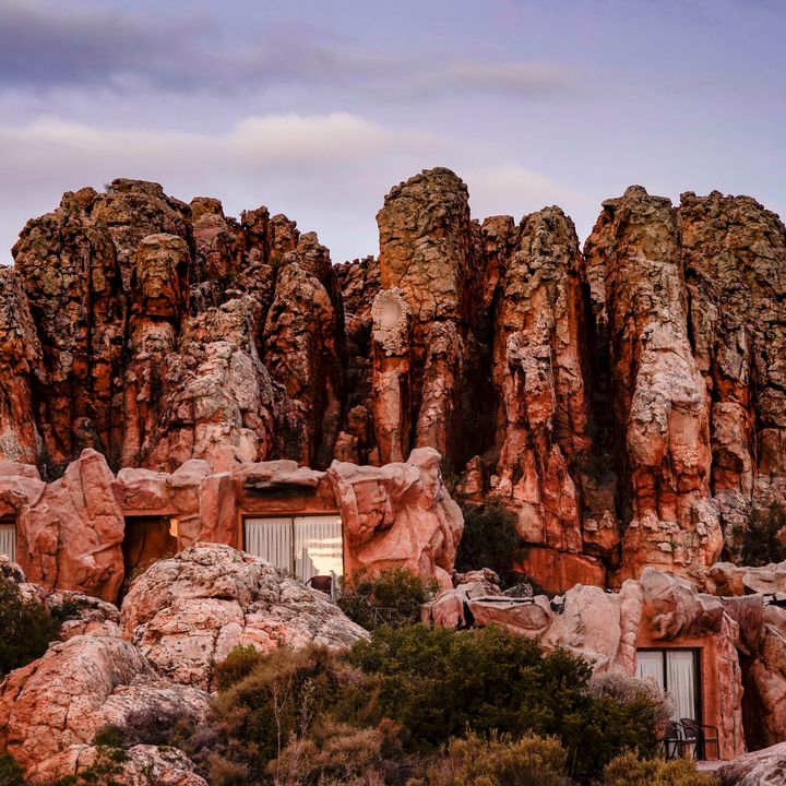 A collection of cave hotel rooms nearly hidden into the side of a rugged mountain at Kagga Kamma Eco Lodge.
