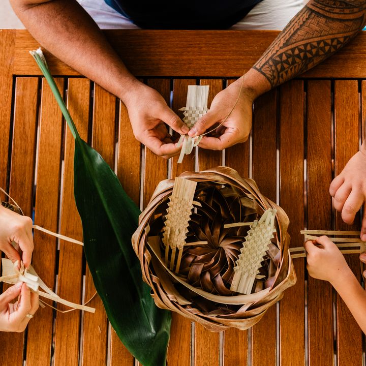 Hands are seen from overhead taking part in a weaving class at Outrigger Ka'anapali Beach Resort.
