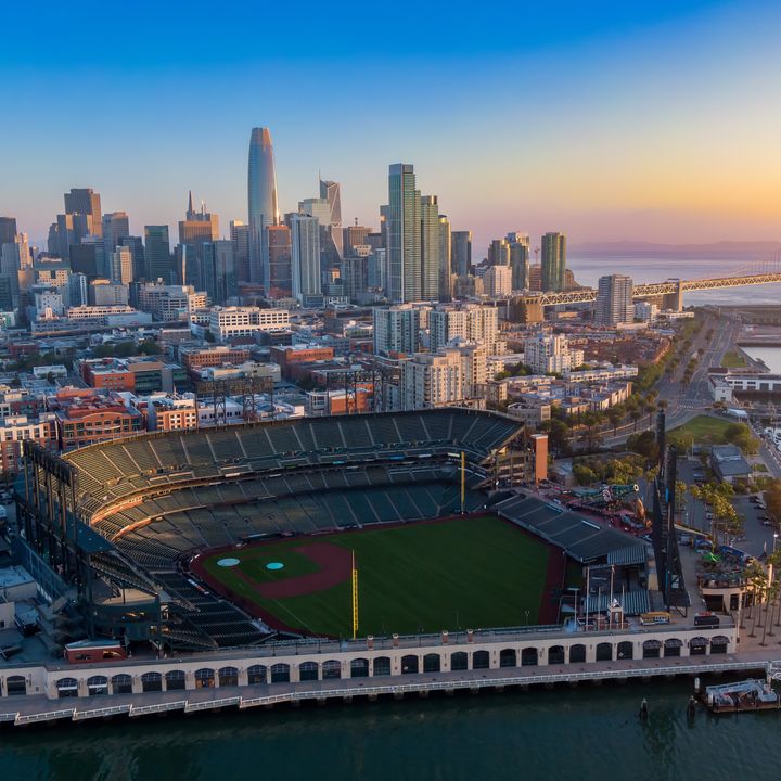 An aerial view over Oracle Park, home of the San Francisco Giants, in San Francisco with views of the city skyline behind it.