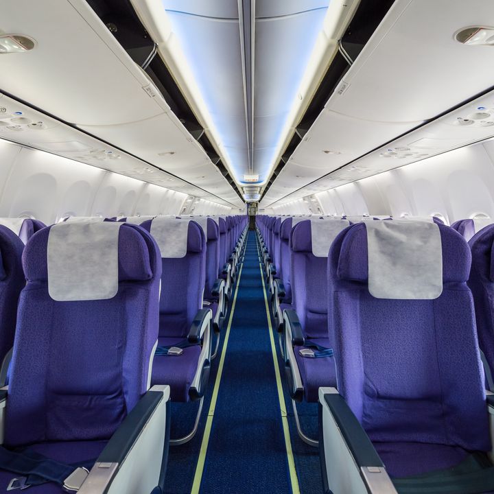 Rows of purple airplane seats in an empty plane cabin.