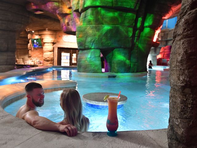 A couple sitting inside an indoor pool lit up with lights.