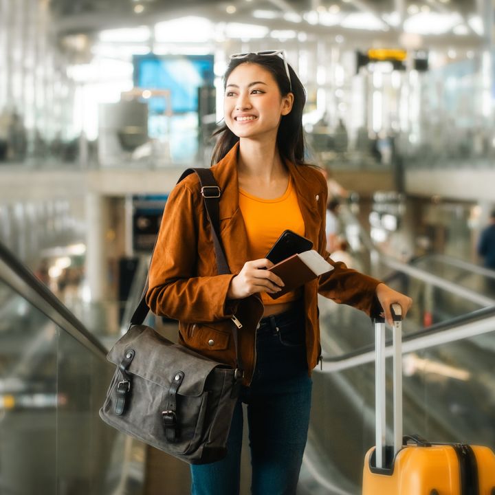 Smiling young woman holding passport in the airport