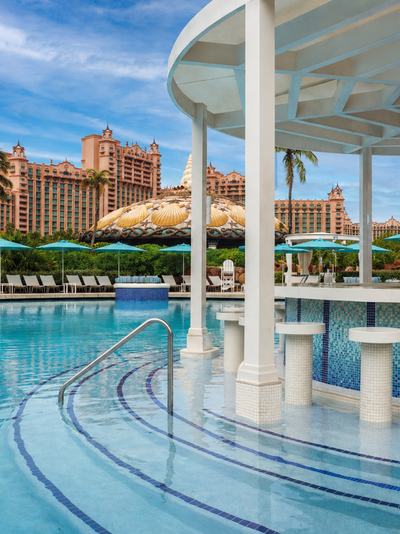 The in-pool Coral Bar at Atlantis Paradise Island with steps in the pool leading up to a circular bar with stools in the pool.