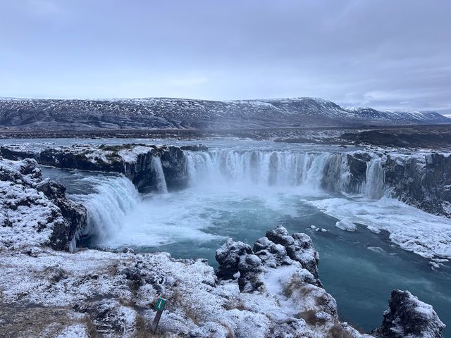 A small range or waterfalls surrounded by icy rock and mountains.