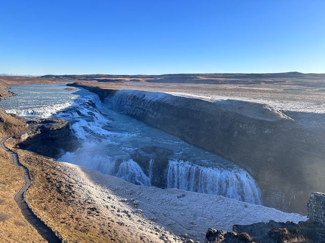 A scenic shot of the massive Gulfoss waterfall in Iceland surrounded by beautiful landscapes.