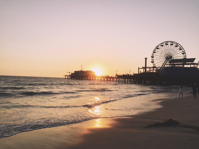 The beach in Santa Monica as seen at sunset with the pier with a ferris wheel.