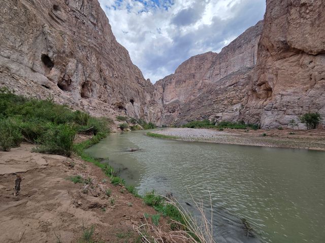 A river in Big Bend National Park inside a canyon with towering mountains on either side of the water.