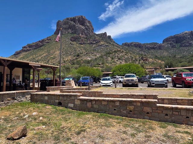 Cars in a parking lot next to a building that says visitor center in Big Bend National Park with Lost Mine Trail in the background.