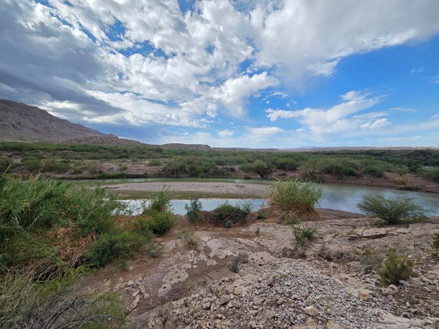 The Rio Grande River in Big Bend National Park, as seen from across a grassy and rocky landscape.