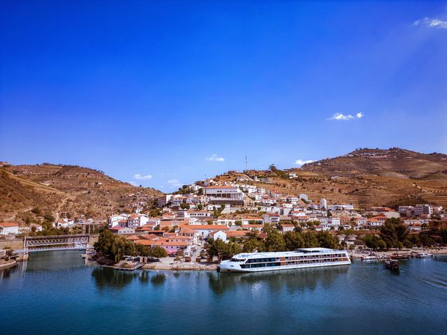 An AmaWaterways ship in port in Europe next to a small coastal village.