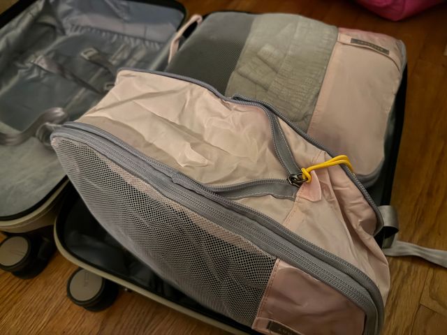 Two full packing cubes inside one clamshell half of a suitcase, with one turned on its side to show the zippers.