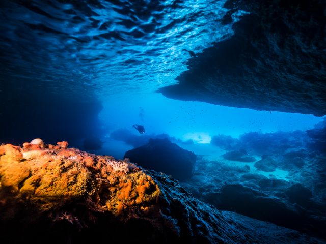 An underwater view of the blue room in Curacao with a diver and rock formations.