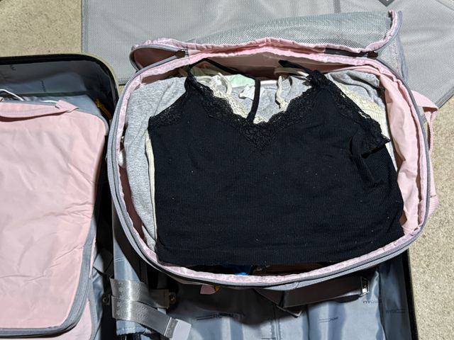An open packing cube inside a suitcase with clothes neatly folded and stacked inside.