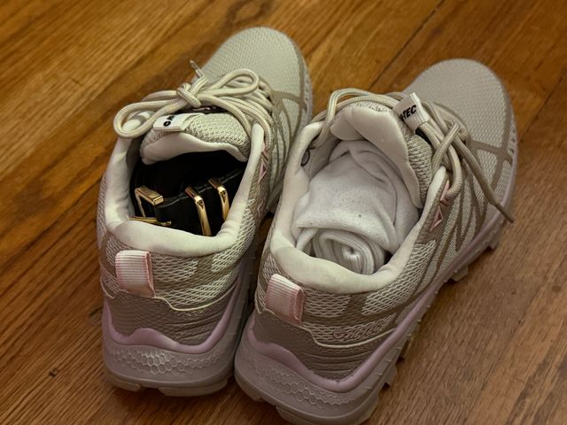 A pair of sneakers with small items stuffed into the inside of each shoe.