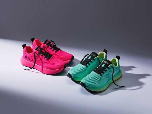 Pink and green Nobull sneakers with a spotlight on them on a gray background.