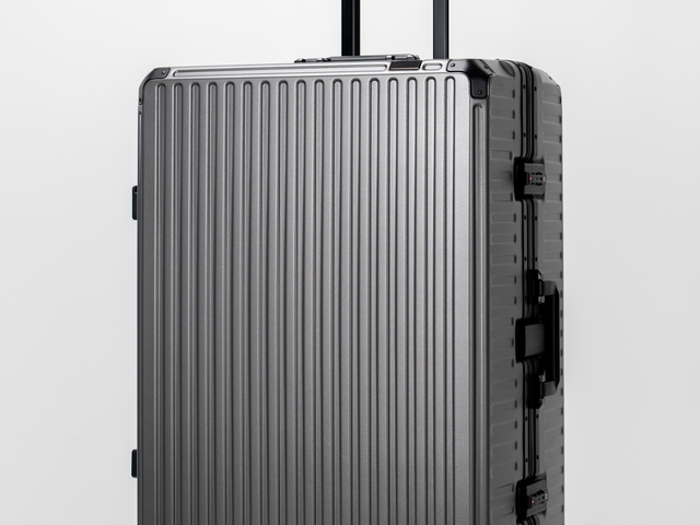 A silver aluminum suitcase with a black handle and black accents against a white background.