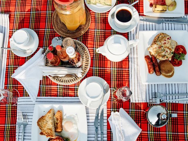An overhead view of a table set with a plaid red tablecloth and plates of food.