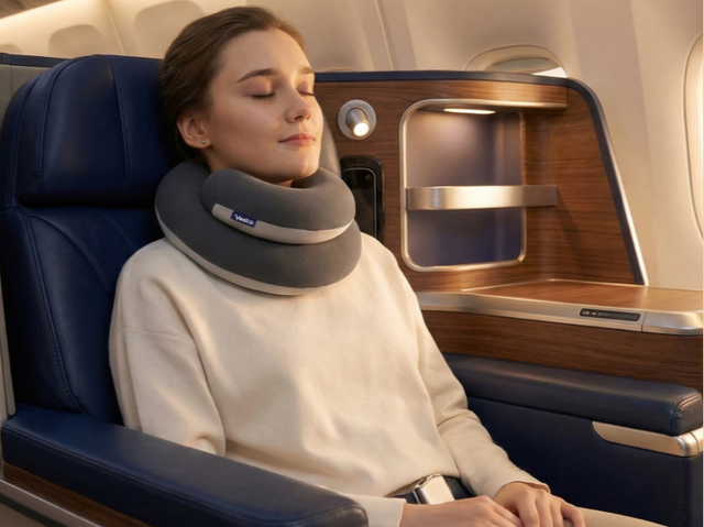 A woman sleeps on a plane wearing a coiled-up neck pillow.