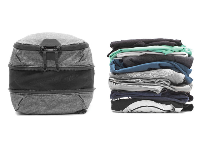 A full packing cube with an equal-sized stack of clothes next to it, against a white background.