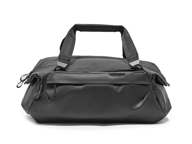 A back duffel with carrying straps suspended in the air, against a white background.