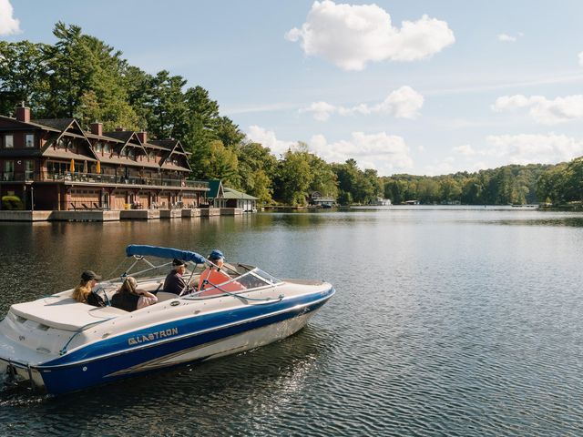 A boat coasting along the waters in Muskoka, with lakeside homes to the left and greenery to the right.