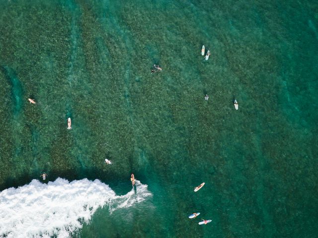 An overhead aerial shot of surfers in the water at The Ritz-Carlton O'ahu, Turtle Bay.