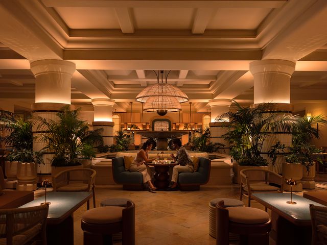Two people eat with chopsticks inside the stylish dining area of Komo at the Four Seasons Resort Maui.