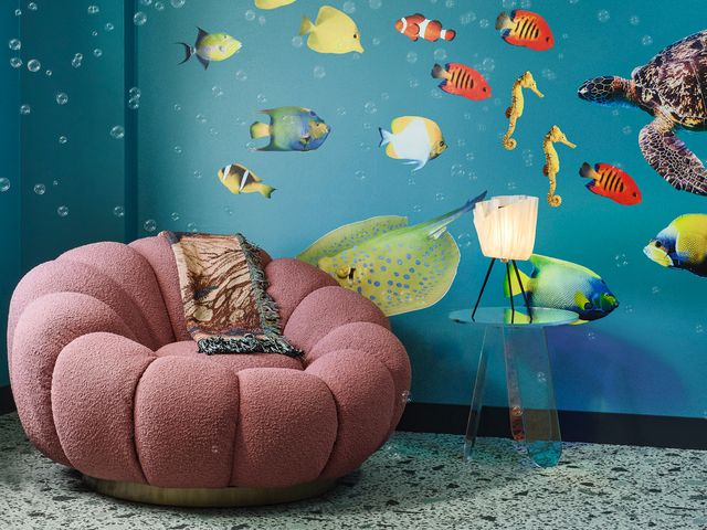 An under the sea themed room at The Curtis with a pink shell chair and fish wallpaper.