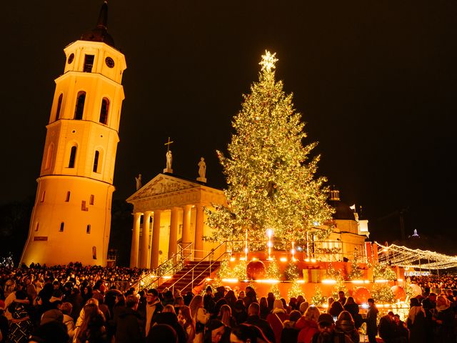 Crowds gather around a lit Christmas tree at night at the Cathedral Square Christmas Market in Vilnius, Lithuania.