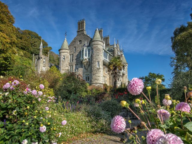 A castle with towers and turrets framed by pretty flowers at Chateau Rhianfa.