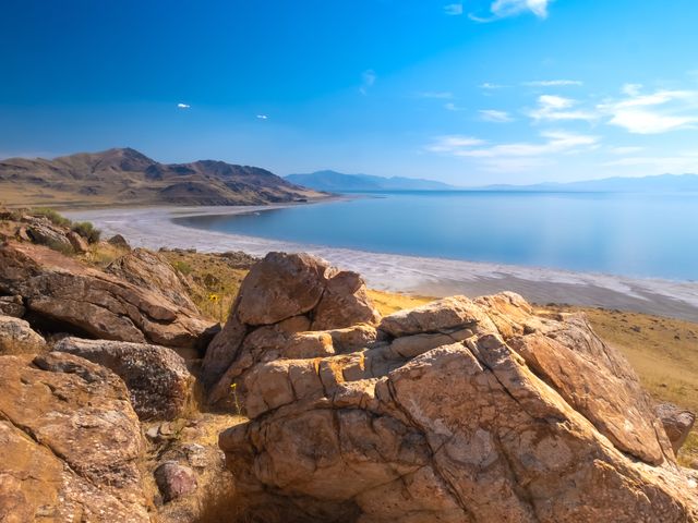 A rocky shoreline in Antelope Island with large tan-colored boulders near the water's edge.