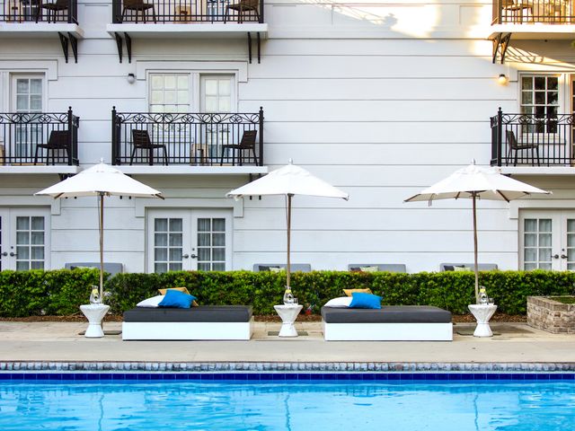 The pool area with umbrellas and lounge benches at Kimpton Hotel Brice.