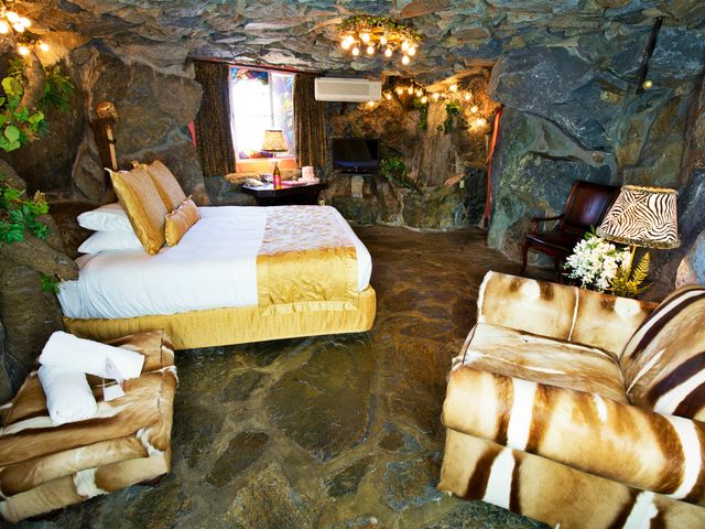 The Caveman room at Madonna Inn with rock walls, animal-print upholstery, a bed, and a chair.