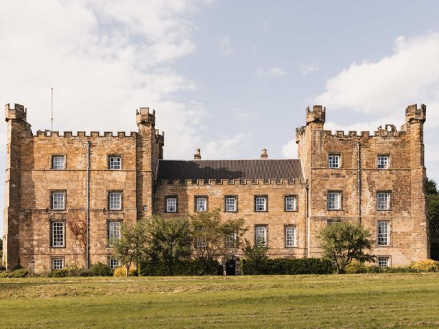 The exterior of Lumley Castle in England with its stone walls, towers, and rows of windows.