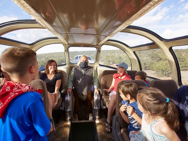 A train with domed windows filled with passengers of all ages.