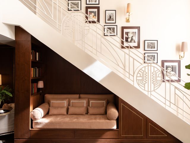 A staircase with a gallery wall of framed photos along the white wall behind it, and a small couch tucked underneath.