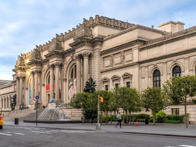 An street view of the exterior of the Met museum in NYC with its grand steps and entrance with columns.