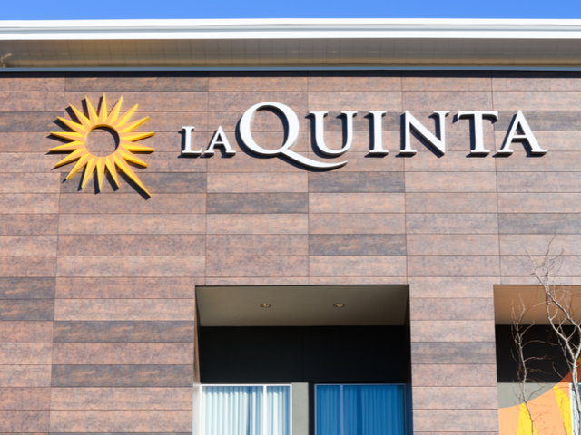 The La Quinta hotel logo on the side of a brown building.