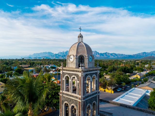 A domed tower stands in front of a town with only the top portion visible, towering over green trees and mountains in the distance.