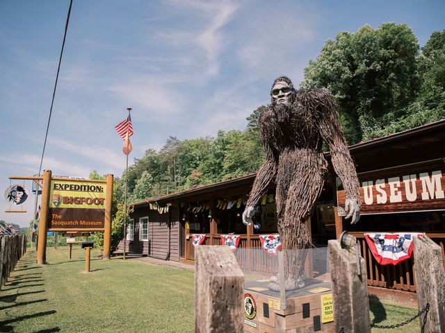 A large Bigfoot statue outside of a building that says museum with trees behind it.