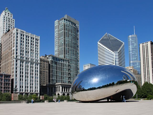 A large silver sculpture in Chicago known as the Bean next to the city skyline.